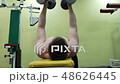 Young athletic man trains pectoral muscles in the gym with dumbbells, engaged in fitness 48626445
