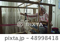 Weaver is adjusting vintage wooden weaving machine 48998418