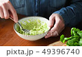 Person mashing avocado in bowl on wooden table 49396740