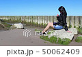 young woman sitting on a stone by the sea 50062409