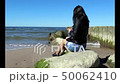 young woman sitting on a stone by the sea 50062410
