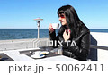 young woman drinking coffee in an outdoor cafe 50062411