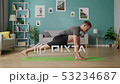 Dolly out of adult man doing yoga in the morning in his living room 53234687