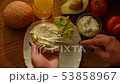 Woman spreading creamy cheese on avocado toast 53858967