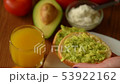 Woman spreading creamy cheese on avocado toast 53922162