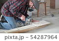 Worker in a plaid shirt and respirator cuts tiles 54287964