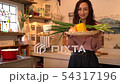 Smiling woman looking at camera with lots of vegetables in the kitchen 54317196