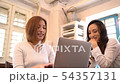 Two Japanese women talking while looking at laptop 54357131