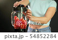 A young woman puts tomatoes in to the blender and turns it on . Close up 54852284