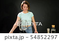 A young woman is cooking raw gazpacho. She puts tomatoes in the blender 54852297
