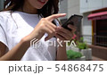 Woman operating a smartphone outdoors Zoom & Close up 54868475