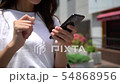 Close-up of a woman's hand operating a smartphone outdoors (without face) 54868956
