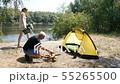 A man kindles a fire. The girl brings chairs to the tent. Tourism, travel, green tourism concept 55265500