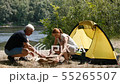 A man and a girl make a fire. Tourism, travel, green tourism concept. River and forest in the 55265507