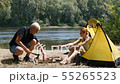 Young female traveler is sitting in the tent. The girl passes the man a cup of tea. The man drinks 55265523