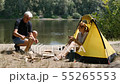 A man chopping wood near the tent. The girl laughs sitting in a tent. Hiking, travel, green tourism 55265553
