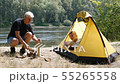 Young woman traveler sleeps in a tent. A man approaches the tent and starts chopping wood for the 55265558