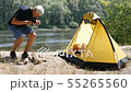 Young woman traveler sleeps in a tent. A man approaches the tent and starts chopping wood for the 55265560
