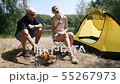 A man and a girl roasting marshmallows on a fire. Marshmallow ready. The girl eats marshmallows 55267973