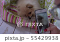 A woman filming a playful cute dog with her phone 55429938
