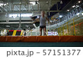 In the trampoline hall, a girl jumps on a trampoline in an unusual way. Landing on the ass 57151377