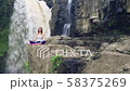 Woman sitting in yoga lotus pose on the edge next to Tegenungan Waterfall 58375269