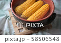 Setting a pot with steamed corn cobs on a table 58506548