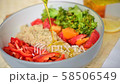 Adding olive oil and squizzing a lemon into Buddha bowl with quinoa, tomato, sliced red pepper and steamed broccoli 58506549