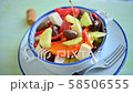 Pouring olive oil onto Greek salad with feta cheese, Kalamata olives, cucumber, tomato 58506555