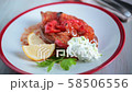 Putting two spoons of tzatziki onto a plate with a portion of Imam Bayildi, Turkish dish, an oven baked eggplant stuffed with vegetables 58506556