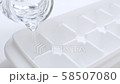 pouring fresh drink water from a jug into ice cube tray 58507080