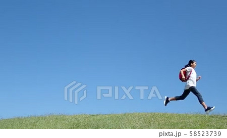 青空で走る小学生の女の子（スローモーション）の動画素材 [58523739]