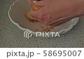 Female hands breaking soaked in water bread in a white bowl. Preparing italian salad Panzanella with dry bread. 58695007