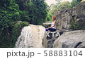 Woman sitting in yoga lotus pose on the edge next to Tegenungan Waterfall 58883104