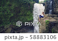 Woman sitting on a cliff next to Tegenungan Waterfall 58883106