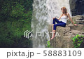 Woman sitting on a cliff next to Tegenungan Waterfall 58883109
