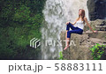 Woman sitting on a cliff next to Tegenungan Waterfall 58883111
