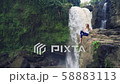 Woman sitting on a cliff next to Tegenungan Waterfall 58883113