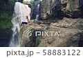 Woman sitting on a cliff next to Tegenungan Waterfall 58883122