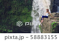 Woman sitting on a cliff next to Tegenungan Waterfall 58883155
