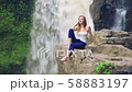 Woman sitting on a cliff next to Tegenungan Waterfall 58883197