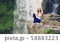 Woman sitting on a cliff next to Tegenungan Waterfall 58883223