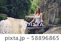 Woman sitting in yoga lotus pose on the edge next to Tegenungan Waterfall 58896865