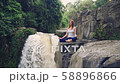 Woman sitting in yoga lotus pose on the edge next to Tegenungan Waterfall 58896866