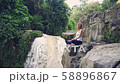 Woman sitting in yoga lotus pose on the edge next to Tegenungan Waterfall 58896867