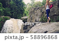 Woman walking to the edge of Tegenungan Waterfall to do yoga 58896868