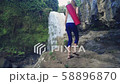 Woman walking to the edge of Tegenungan Waterfall to do yoga 58896870