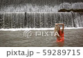 Young unrecognizable woman in orange dress standing on background of big waterfall. Back view.  59289715