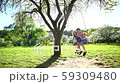 Happy brother and sister swinging on swing on sunny day in spring. Static shot 59309480