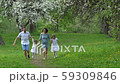 parents and daughters run in spring park in blooming tree garden. Slow motion 59309846